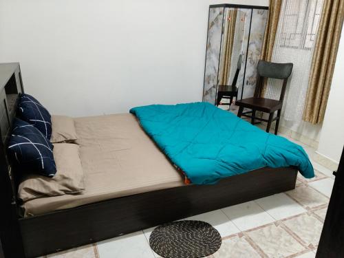 a bed with a blue blanket on it in a room at Tulip - Shillong in Shillong