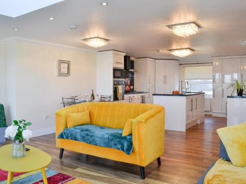 a living room with a yellow couch and a kitchen at Ailsa Craig View in Stranraer