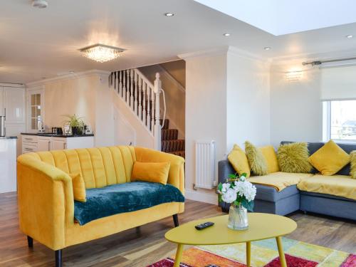 a living room with a yellow couch and a table at Ailsa Craig View in Stranraer