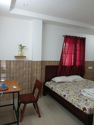 a bedroom with a bed and a table and a red curtain at Orchid Woods Room in Trivandrum