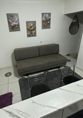 a living room with a couch and some flowers on the wall at KITNET mobiliada com ar condicionado in Guarujá