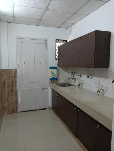 an empty kitchen with a sink and a door at Orchid Woods Room in Trivandrum