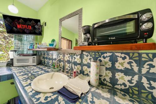 a bathroom with a sink and a microwave on a counter at Casa Cielo Studio 1 with Tropical Garden Patio in Isla Mujeres