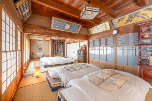 two beds in a room with wooden ceilings and windows at 岐阜羽島の隠れ家 古民家cocone in Hashima