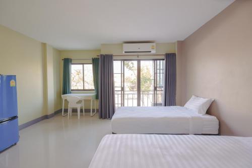a hotel room with two beds and a table at V Tharm Hotel in Udon Thani