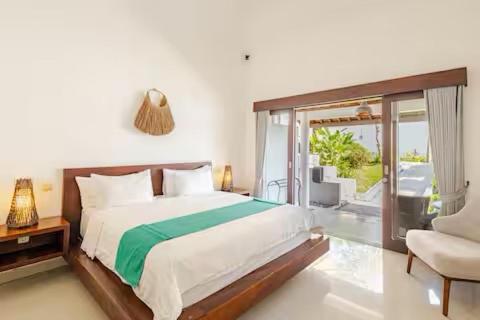 a bedroom with a bed and a window and a chair at Villa Leelavadee in Uluwatu