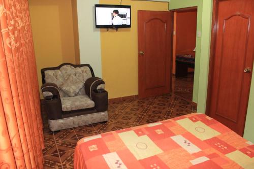 um quarto com uma cadeira e uma televisão na parede em Residencial Norandes em Huaraz