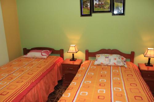 two beds in a room with two lamps on tables at Residencial Norandes in Huaraz