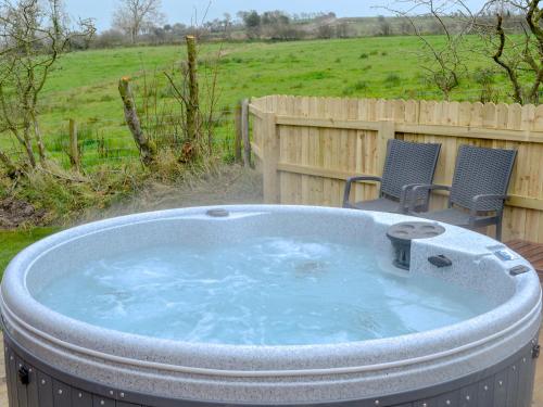 a large hot tub in a yard with two chairs at Skylark Lodge in Westward