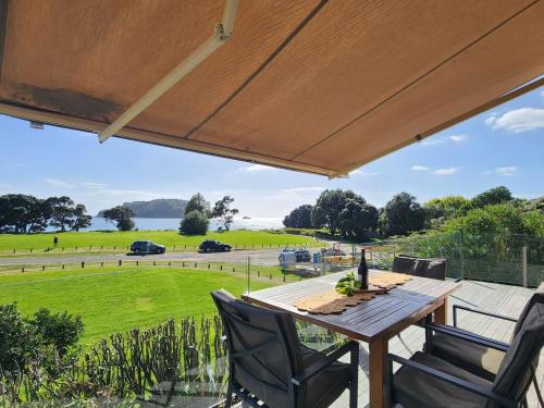 a patio with a table and chairs and a view of a field at Hahei Beachside Escape in Hahei