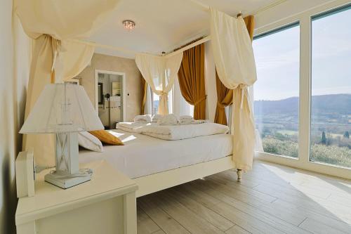 a bedroom with a white bed with a lamp and a window at Relais Villa Olivi in Costermano
