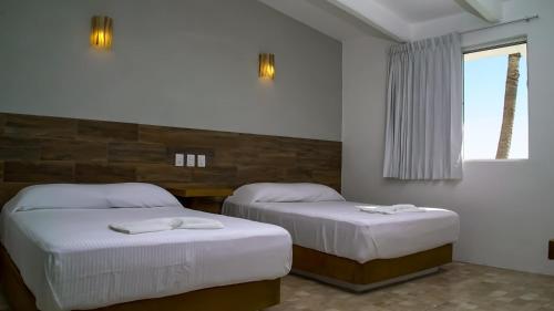 a bedroom with two beds and a window at Hotel Villa Mexicana Puerto Escondido in Puerto Escondido