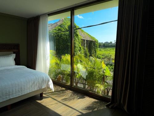 a bedroom with a large window with a view of a yard at Ducat Living in Canggu