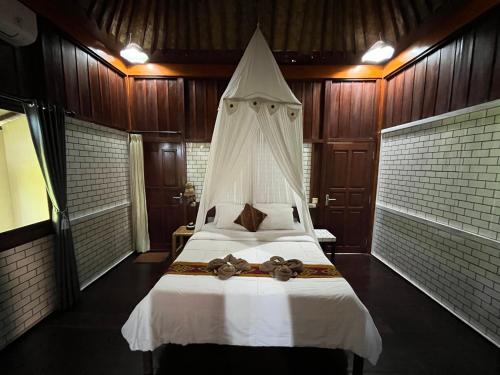 a bedroom with a large white bed with a canopy at Khrisna Hs and Cottages in Sidemen