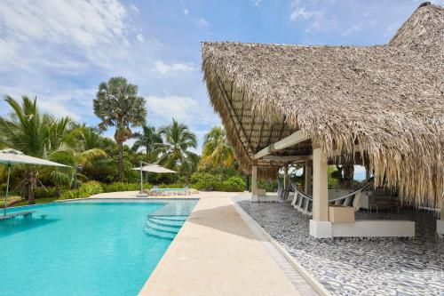 a resort with a swimming pool with a straw roof at Finca Los Mangos in Doradal