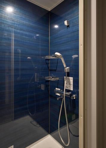 a shower in a bathroom with a blue wall at Hotel Zen in Kyoto