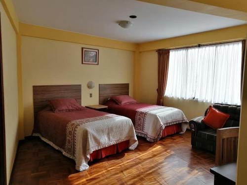 a hotel room with two beds and a chair at Hotel Nuevo Sol in La Paz