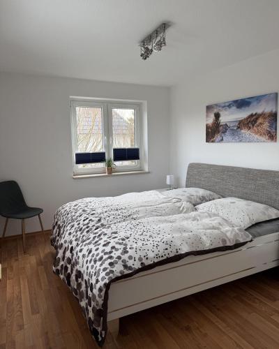 a white bedroom with a bed and two windows at Utholmer-Strasse-3 in Brösum