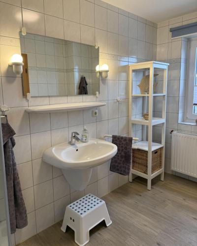 a bathroom with a sink and a mirror and a stool at Utholmer-Strasse-3 in Brösum
