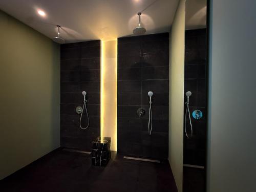 a bathroom with two shower stalls with black tiles at Ducat Living in Canggu