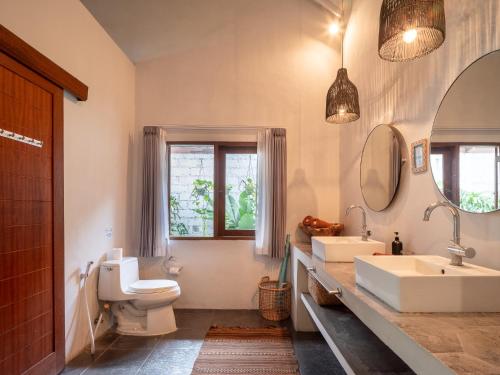 a bathroom with two sinks and a toilet and a mirror at Lila Boutik Canggu in Canggu