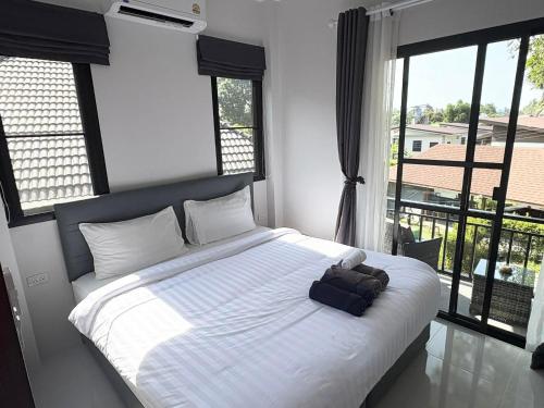 a bedroom with a bed with white sheets and windows at Lucky home in the heart of thongsala in Thong Sala