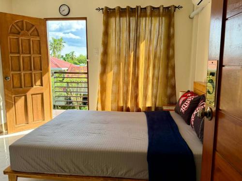 a bedroom with a bed and a door with a window at Henritz Apartelle in Sogod
