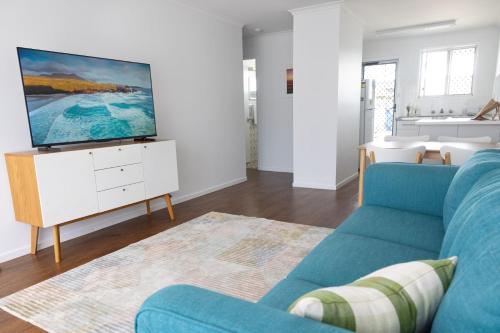 a living room with a blue couch and a tv at 1-45 Beech Street in Evans Head