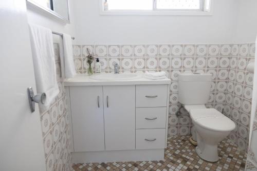 a white bathroom with a toilet and a sink at 1-45 Beech Street in Evans Head