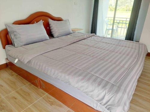 a large bed in a bedroom with a wooden headboard at เจอาร์รีสอร์ท ที่พักบ้านมุงเนินมะปราง in Ban Mung