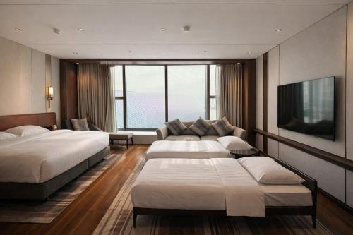 a hotel room with two beds and a couch at Dorsett Kai Tak in Hong Kong