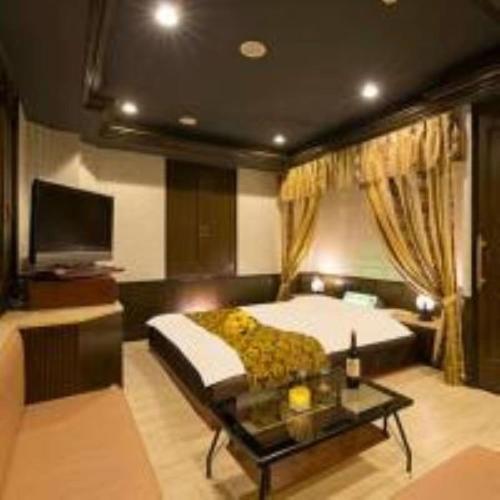 a bedroom with a bed and a table and a tv at かぼちゃの馬車 泉大津大人専用 in Izumiotsu
