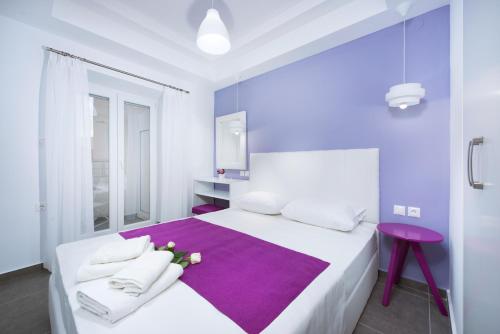 a bedroom with a white bed with purple sheets and a purple rug at La central Apartments in Limenaria