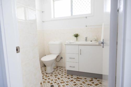 a white bathroom with a toilet and a sink at 2-45 Beech Street in Evans Head