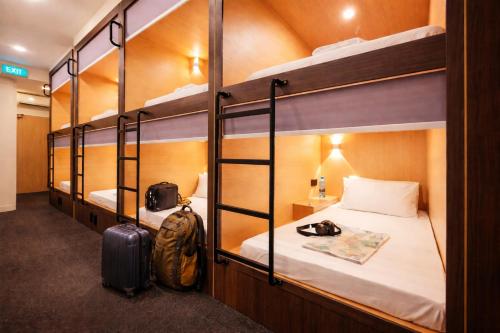 a room with three bunk beds with luggage in it at Wink at Perak Road in Singapore