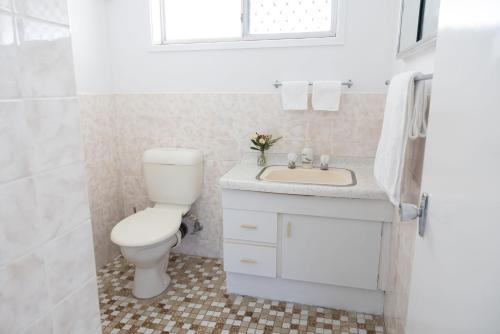 a white bathroom with a toilet and a sink at 4-45 Beech Street in Evans Head