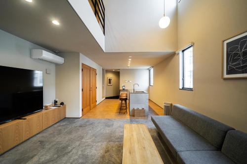a living room with a couch and a flat screen tv at TRIGON Hotel FUKUOKA in Fukuoka