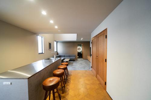 a hallway with a bar with stools and a sink at TRIGON Hotel FUKUOKA in Fukuoka