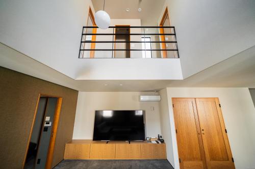 a room with a flat screen tv and a balcony at TRIGON Hotel FUKUOKA in Fukuoka