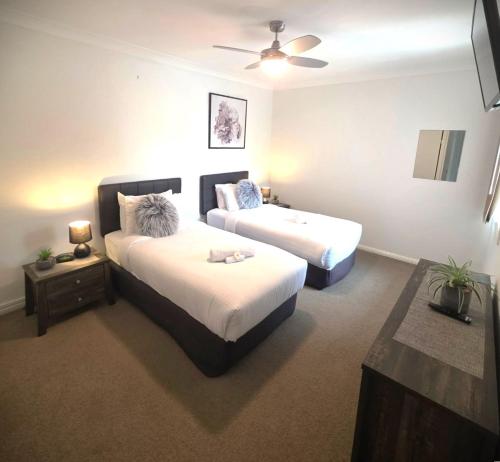 a bedroom with two beds and a ceiling fan at Sandy Toes in Bellara