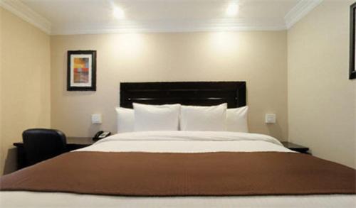 a bedroom with a large bed and a chair at Raincross Hotel Riverside in Riverside
