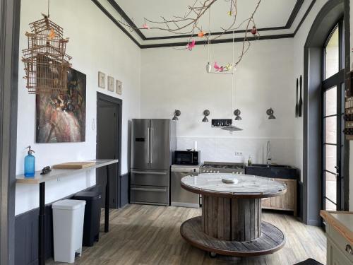 a kitchen with a table and a refrigerator at Petite gare aux oiseaux in Le Châtenet