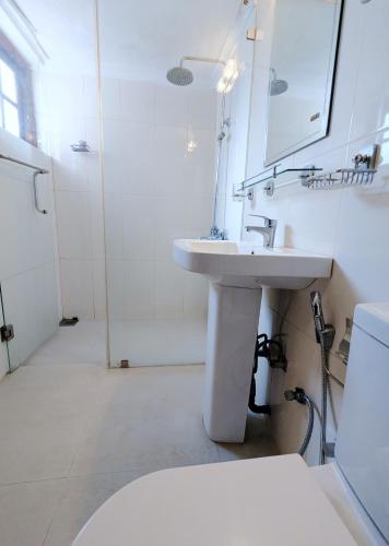 a white bathroom with a sink and a mirror at Hill Crest Mansion in Kandy