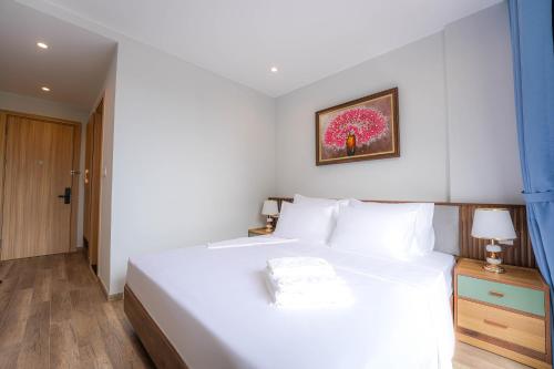 a bedroom with a white bed and a picture on the wall at Leono Coast Beach Hotel Phu Quoc in Phú Quốc