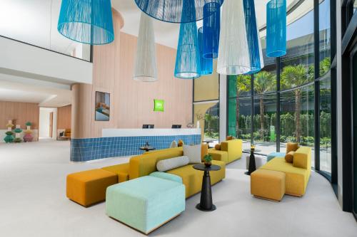 a lobby with yellow and blue furniture and windows at ibis Styles Phuket Bangtao in Bang Tao Beach