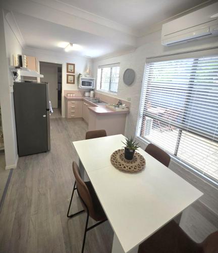 a kitchen with a white table and a refrigerator at Banksia Beach Views! in Banksia Beach