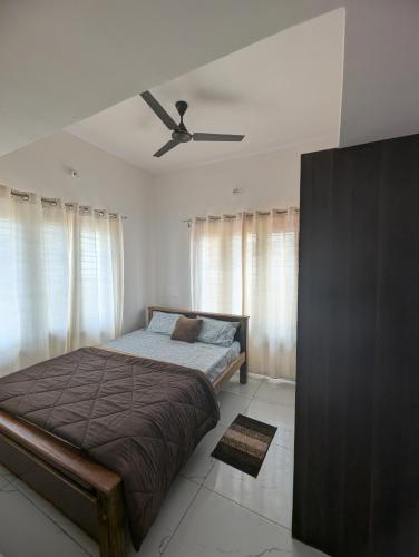 a bedroom with a bed and a ceiling fan at Elite Homes in Chikmagalūr