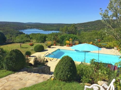 una piscina con sombrilla y un lago en Lovely g te with private pool, en Montagnac