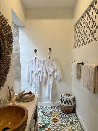 a bathroom with white robes hanging on a wall at Santai Villas in Nusa Lembongan