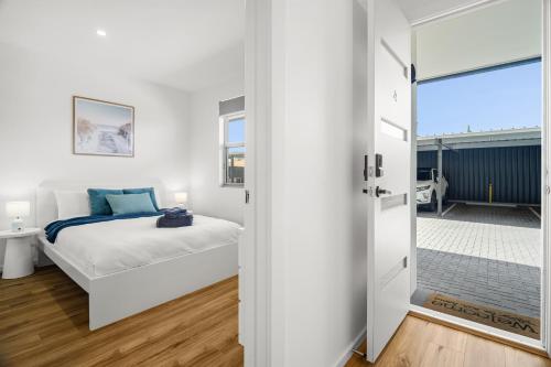 a bedroom with a bed and a door leading to a balcony at Chic Flinders Park Getaway in Adelaide